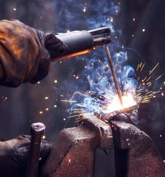 A welding student uses a torch to join two pieces of metal