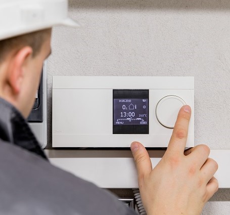 Thumbnail of an HVAC technician programing a smart thermostat for energy-efficient heating and cooling