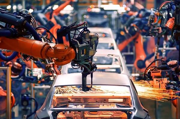 A welding automation arm works on a car on an assembly line