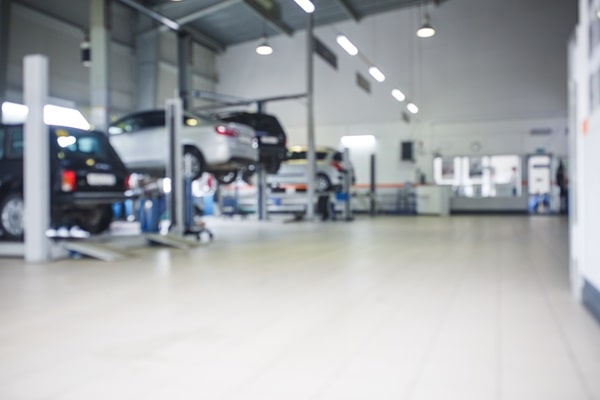Mechanics work on four cars in an automotive shop