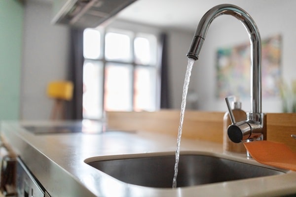 Water flows freely from a kitchen faucet after a plumber adhered to building code compliance