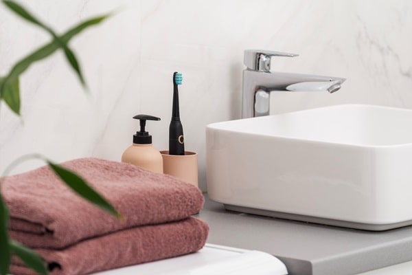 A modern bathroom with a smart faucet, white sink, and clean towels