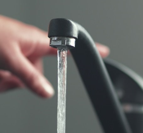 Thumbnail of a person touching a smart faucet that is running with clear, clean drinking water