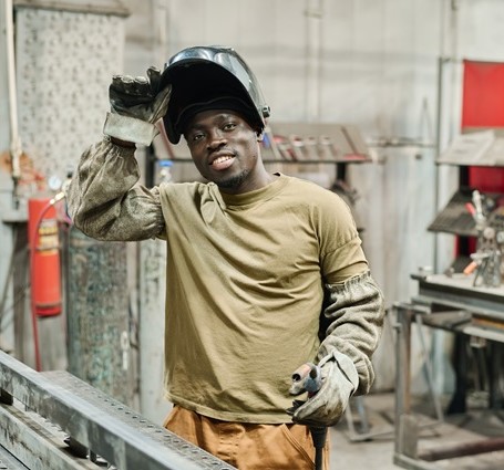 Thumbnail of a welder lifting up his helmet while wearing gloves in the shop