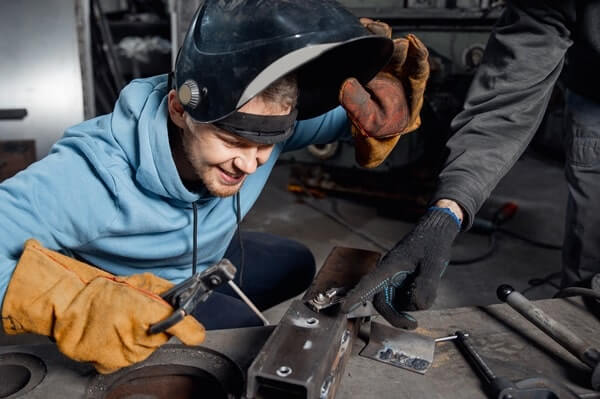 A welder examines his project in welding class