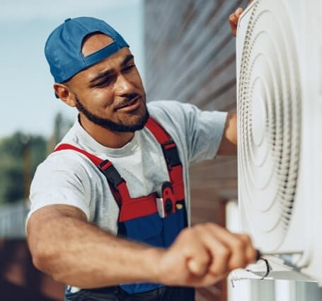 Thumbnail of an A/C technician repairs an air conditioning unit outside