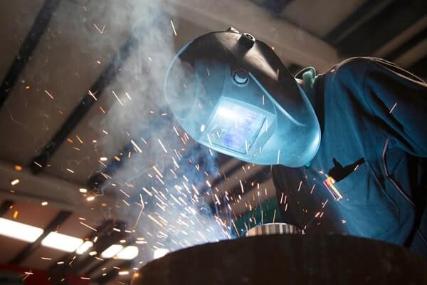 A welder works as sparks fly up around his protective gear